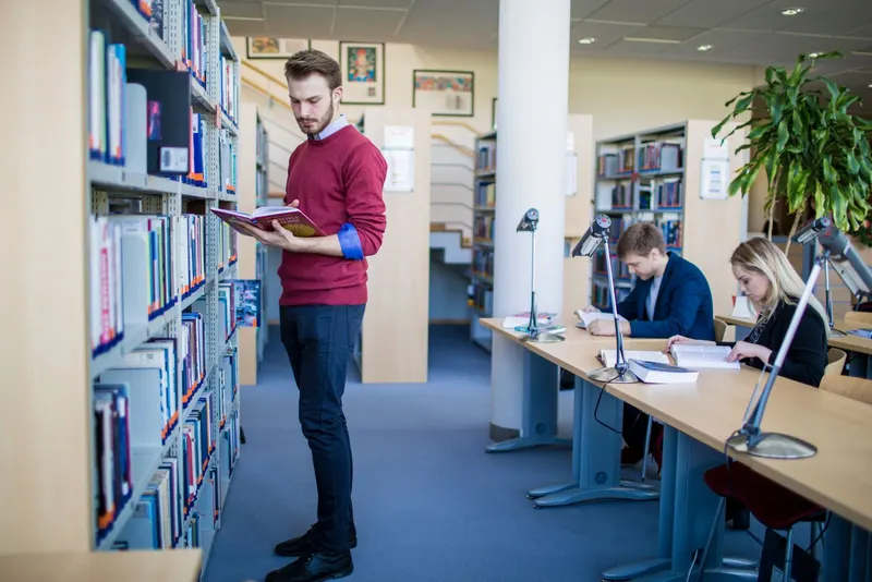 Student przegląda książki w bibliotece